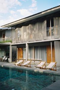 a row of lounge chairs next to a building with a swimming pool at SUNKISS in Bangkok Noi