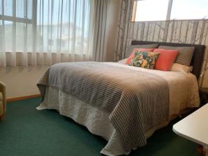 a bedroom with a bed with pillows and a window at Brook House B&B & Cottages in Kaikoura