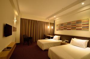 a hotel room with two beds and a desk at StarCity Hotel in Alor Setar