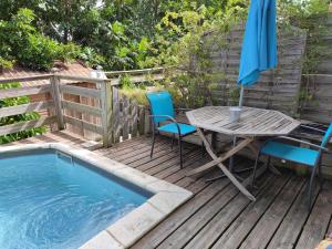 a wooden deck with a table and chairs next to a pool at Apartment Moulins in Le Moule