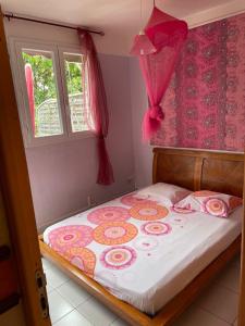 a bedroom with a bed with a pink comforter at Apartment Moulins in Le Moule