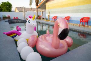 a pool with a pink and white inflatable horse and swans at The Getaway Bermuda Dunes- Saltwater Pool, Spa, Firepit, Coachella in Bermuda Dunes
