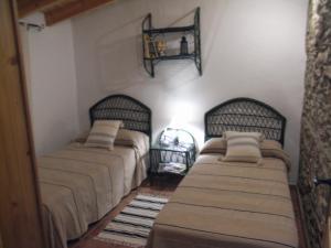 a bedroom with two beds and a shelf on the wall at La Casilla del Pastor in Vélez-Málaga