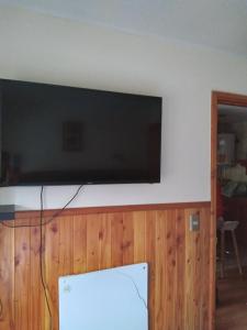 TV de pantalla plana colgada en la pared en Departamento camino al volcán, en Pucón