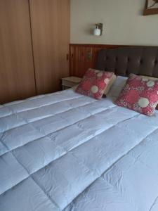 1 cama blanca grande con 2 almohadas en Departamento camino al volcán, en Pucón