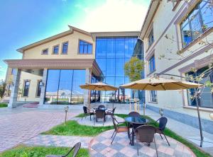 a group of tables with umbrellas in front of a building at Boutique Hotel Silk Way in Türkistan