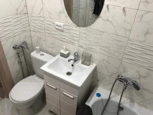 a bathroom with a sink and a toilet and a mirror at Квартира-студия в центре с балконом с белым постельным, рядом с Dostyk Mall in Petropavlovsk