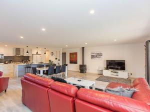 a living room with red leather furniture and a kitchen at Jindalee 1 11 Twynam Street in Jindabyne