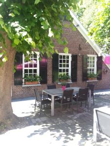 een tafel en stoelen voor een bakstenen gebouw bij Hotel Boerderij Restaurant De Gloepe in Diffelen