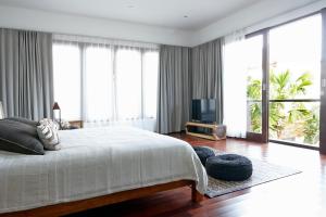 a bedroom with a large white bed and large windows at Villa Ziba in Seminyak