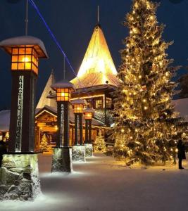 a christmas tree in front of a building with lights at Apartment Sanctus Nicolaus with sauna in Rovaniemi