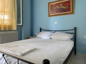 a bed with white sheets and a painting on the wall at Alexandras Appartments in Igoumenitsa