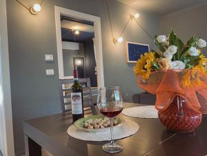 a table with a glass of wine and a vase of flowers at WellHome Asti Premium Apartments with Private Terrace & Garden in Asti +60 photos