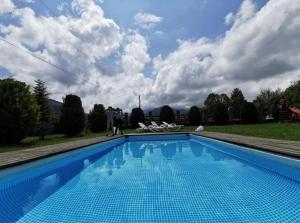 a large blue swimming pool with people standing around it at Casa Csiki in Râşnov