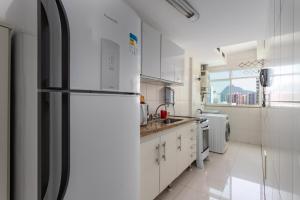 uma cozinha com armários brancos e um frigorífico em Bora Bora Resort Barra da Tijuca no Rio de Janeiro