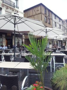 a patio with tables and chairs with umbrellas at Hotel du Pot d'Etain in Châlons-en-Champagne