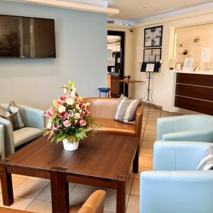 a living room with a table with flowers on it at KomfortHotel Grossbeeren - Stadt-Gut-Hotel in Großbeeren