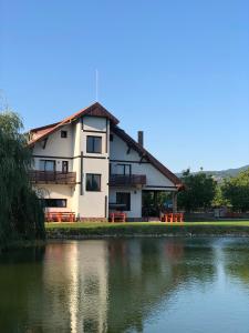 a large white house with a lake in front of it at Pensiunea Trecatoarea Lupilor in Burda