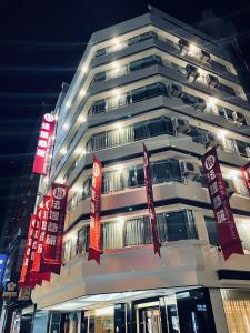 ein hohes weißes Gebäude mit roten Schildern darauf in der Unterkunft Felicity Business Hotel in Taichung
