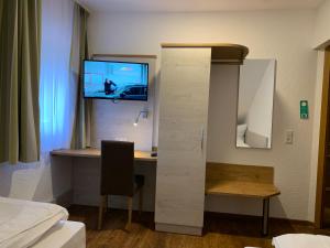 a room with a desk and a tv on a wall at Hotel Waibstadter Hof in Waibstadt