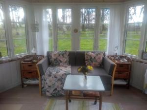 a living room with a couch and a table and windows at Romantik og idyl in Dybvad