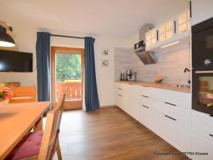 uma cozinha com armários brancos, uma mesa e uma janela em Appartement Petra em Kössen
