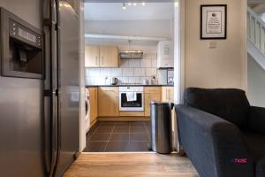 a kitchen with a stainless steel refrigerator and a couch at Host Liverpool - Artsy Stadium Suite, City Center & Garden in Liverpool