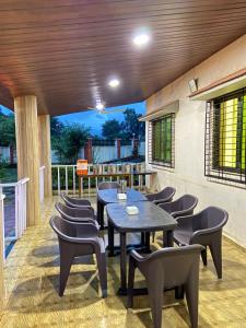 a patio with tables and chairs on a deck at Karjat retreat 4bhk pvt farmhouse in Karjat