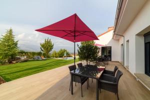 een tafel met een rode parasol op een patio bij Apartamentos Rurales La Gloria de Yuste in Jaraiz de la Vera