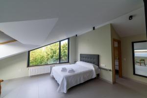een slaapkamer met een bed en 2 grote ramen bij Apartamentos Rurales La Gloria de Yuste in Jaraiz de la Vera