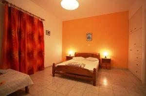 a bedroom with two beds and an orange wall at Antonio Studios in Naxos Chora