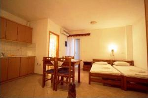 a room with two beds and a table and a kitchen at Antonio Studios in Naxos Chora