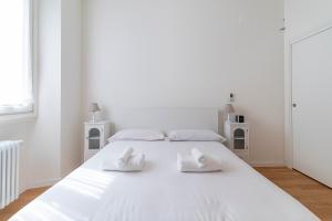 een witte slaapkamer met een groot wit bed en 2 witte handdoeken bij Cosy 1-bed near Milano Centrale in Milaan
