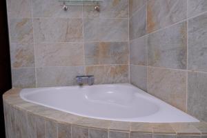 La salle de bains carrelée est pourvue d'une baignoire blanche. dans l'établissement Selina Airport Lodge #Emzini, à Kempton Park