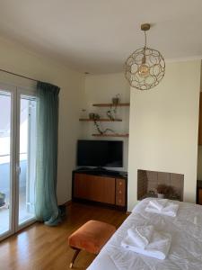 a bedroom with a bed and a television and a chandelier at Zenmar in Zakynthos Town