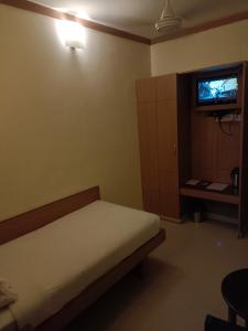 a bedroom with a bed and a tv on the wall at Hotel A P in Coimbatore