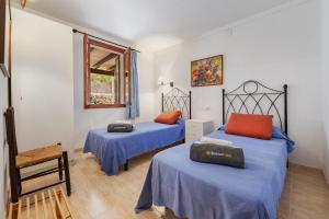 a bedroom with two beds and a chair and a window at Villa Passaró in Port de Pollensa