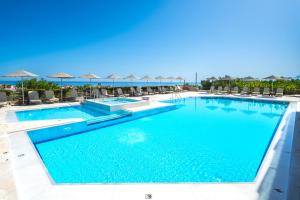 einen Pool mit Stühlen und Sonnenschirmen in einem Resort in der Unterkunft Forest Park Hotel in Rethymno