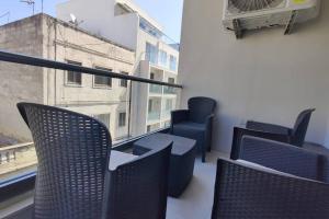 d'un balcon avec des chaises et une vue sur un bâtiment. dans l'établissement Brand new 3 bedroom Apartment close to the sea, à Il-Gżira