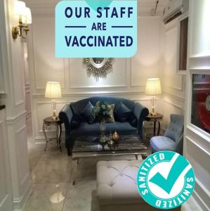 a living room with a couch and a sign that reads our staff are vaccinated at 1 Day Car Hotel Station 18 in Ipoh