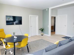 a living room with a couch and a table and yellow chairs at aday - 2 bedroom with modern kitchen and free parking in Aalborg