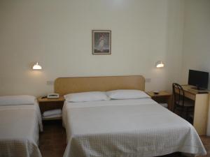 a hotel room with two beds and a television at Hotel La Rusticana in Giardini Naxos