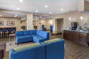 a living room with blue furniture and a kitchen at Comfort Inn & Suites Spring Lake - Fayetteville Near Fort Liberty in Spring Lake