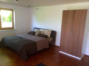 Schlafzimmer mit einem Bett und einem Holzschrank in der Unterkunft Ferienwohnung Blütenweg Kluftern in Friedrichshafen