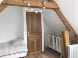 - une chambre avec un lit bébé et une porte en bois dans l'établissement Ferme de la Haute-Escalles, à Escalles