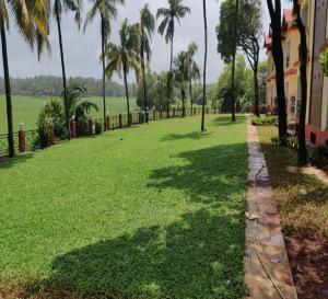 a lawn with palm trees and a building at Sea Queen Beach Resort & Spa in Colva