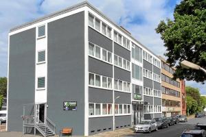 a gray and white building with cars parked in front of it at MB Hotel in Bremen