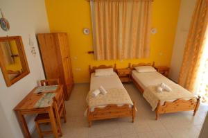 a room with two beds and a table and a table at Marianthi Studios Stegna in Archangelos