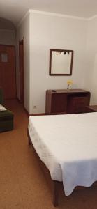 a bedroom with a white bed and a mirror at Pensão Continental Machado in Caldelas