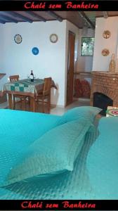 a bedroom with a blue bed with a table and a fireplace at Latvia Chalés in Monte Verde